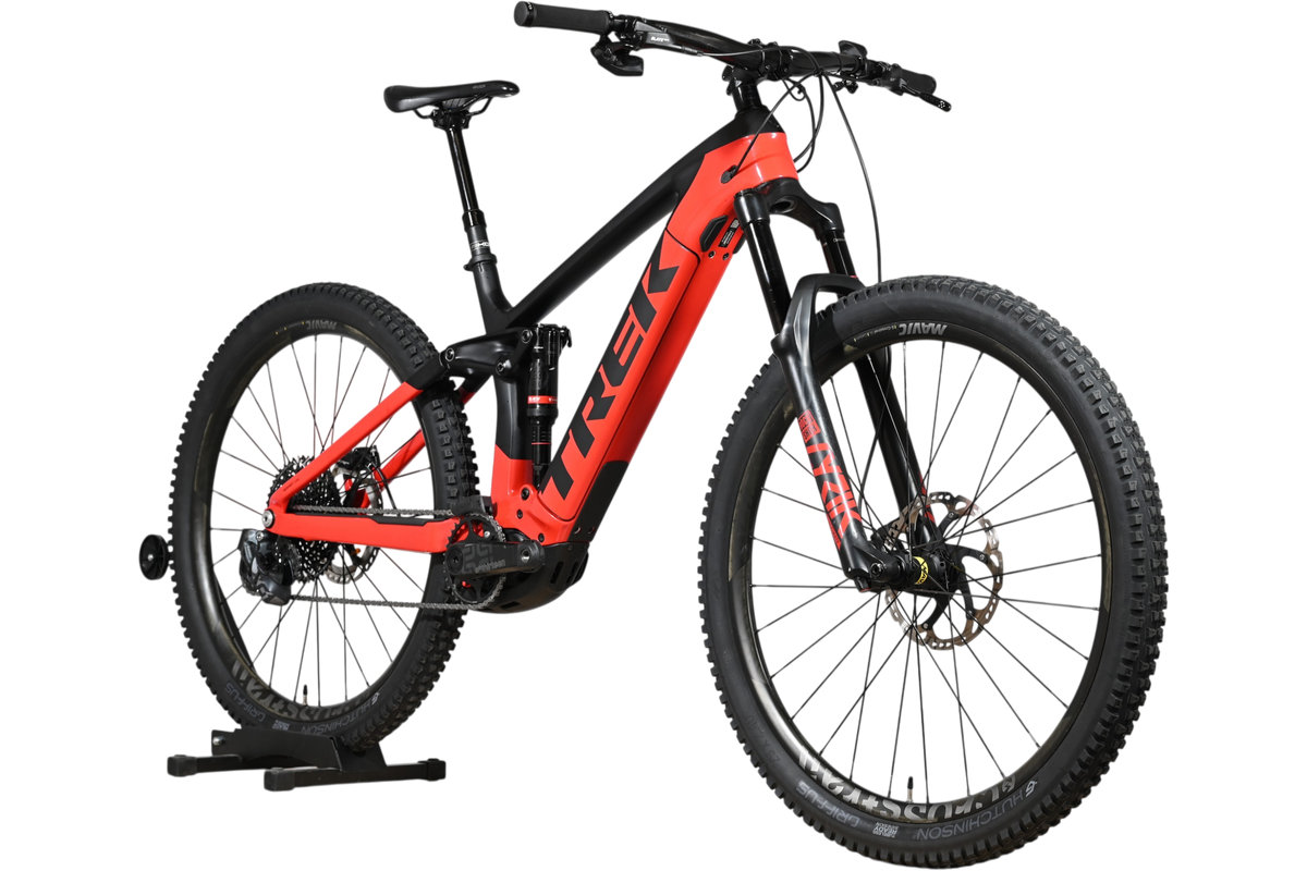 VTT électrique Trek Rail 9.9 2024 rouge et noir de Loop Sports, cadre taille L, vue de profil sur support en bois