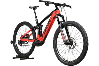 VTT électrique Trek Rail 9.9 2024 rouge et noir de Loop Sports, cadre taille L, vue de profil sur support en bois
