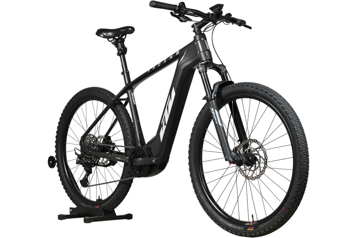 Velo electrique Loop Sports KTM Macina Team noir mat avec cadre robuste et pneus tout-terrain sur support en bois