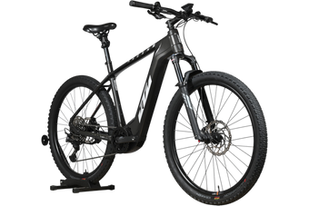 Velo electrique Loop Sports KTM Macina Team noir mat avec cadre robuste et pneus tout-terrain sur support en bois