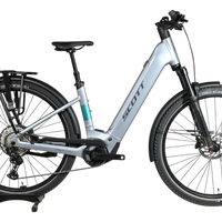Vélo électrique Scott Axis 10 2026 gris clair avec porte-bagages, vendu par Loop Sports sur un socle en bois