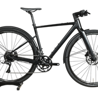 Vélo hybride Scott Metrix 30 EQ 2024 noir mat avec garde-boue, présenté par Loop Sports sur un socle en bois