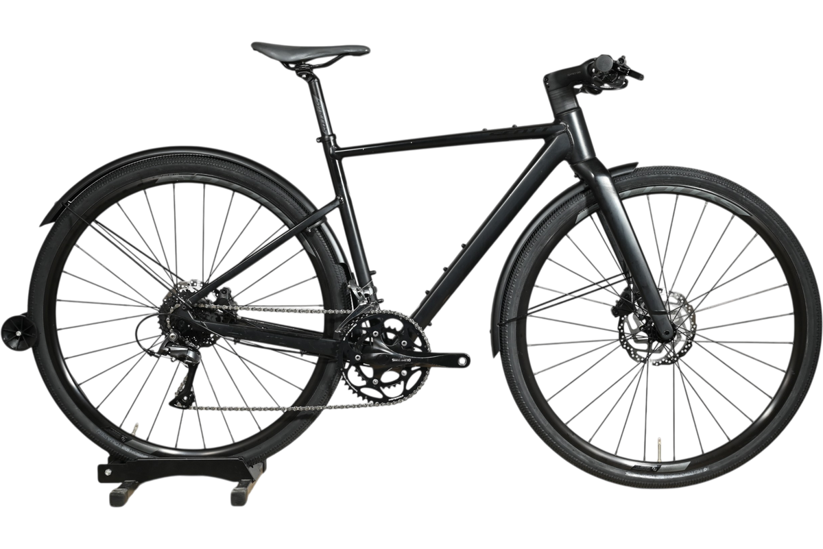 Vélo hybride Scott Metrix 30 EQ 2024 noir mat avec garde-boue, présenté par Loop Sports sur un socle en bois