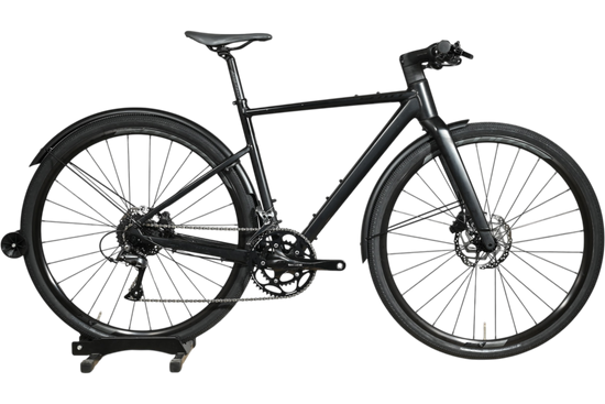 Vélo hybride Scott Metrix 30 EQ 2024 noir mat avec garde-boue, présenté par Loop Sports sur un socle en bois