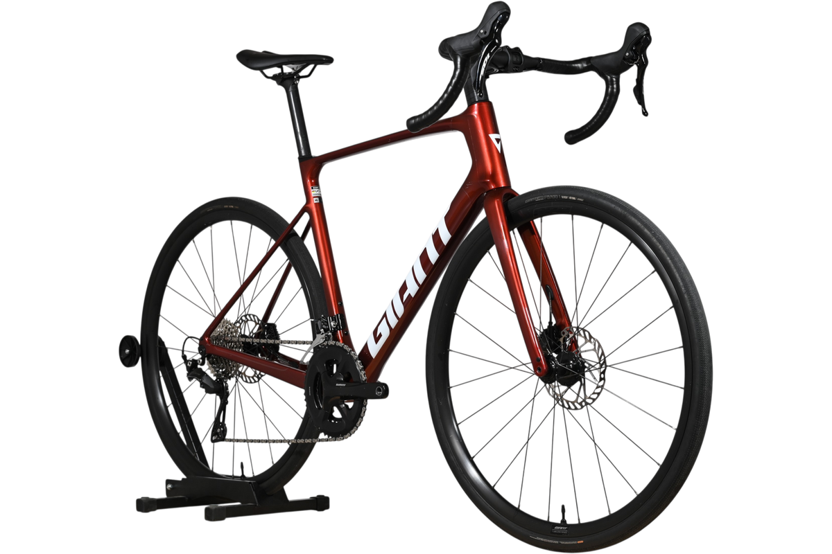 Vélo de route Giant Defy Advanced 2 2025 rouge métallique chez Loop Sports sur support en bois