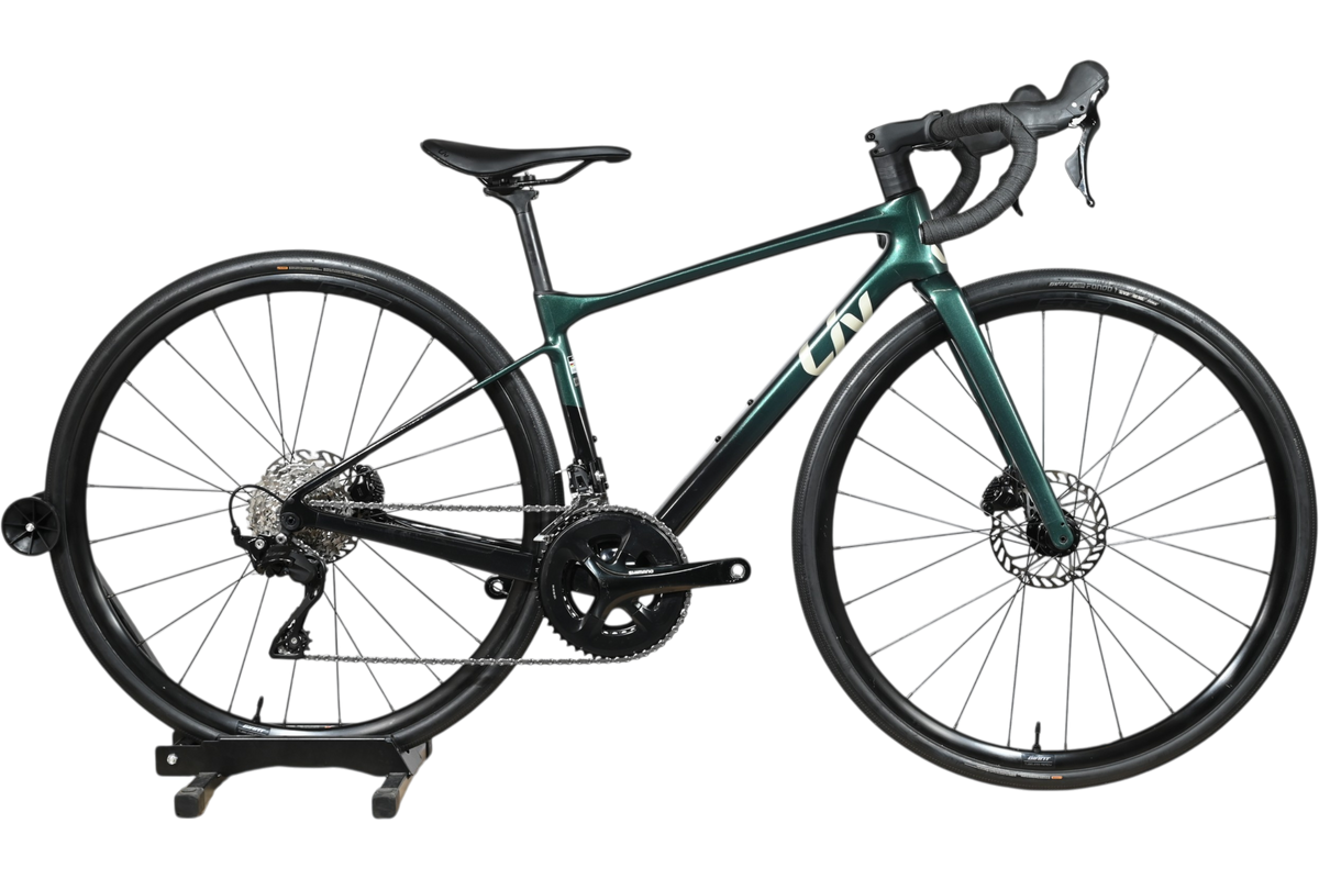 Vélo de route Giant Liv Avail Advanced 2 2025 vert foncé chez Loop Sports sur un support en bois