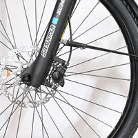 Gros plan sur la roue avant, le frein à disque et la fourche SR Suntour du vélo électrique Loop Sports Velodeville AEB890