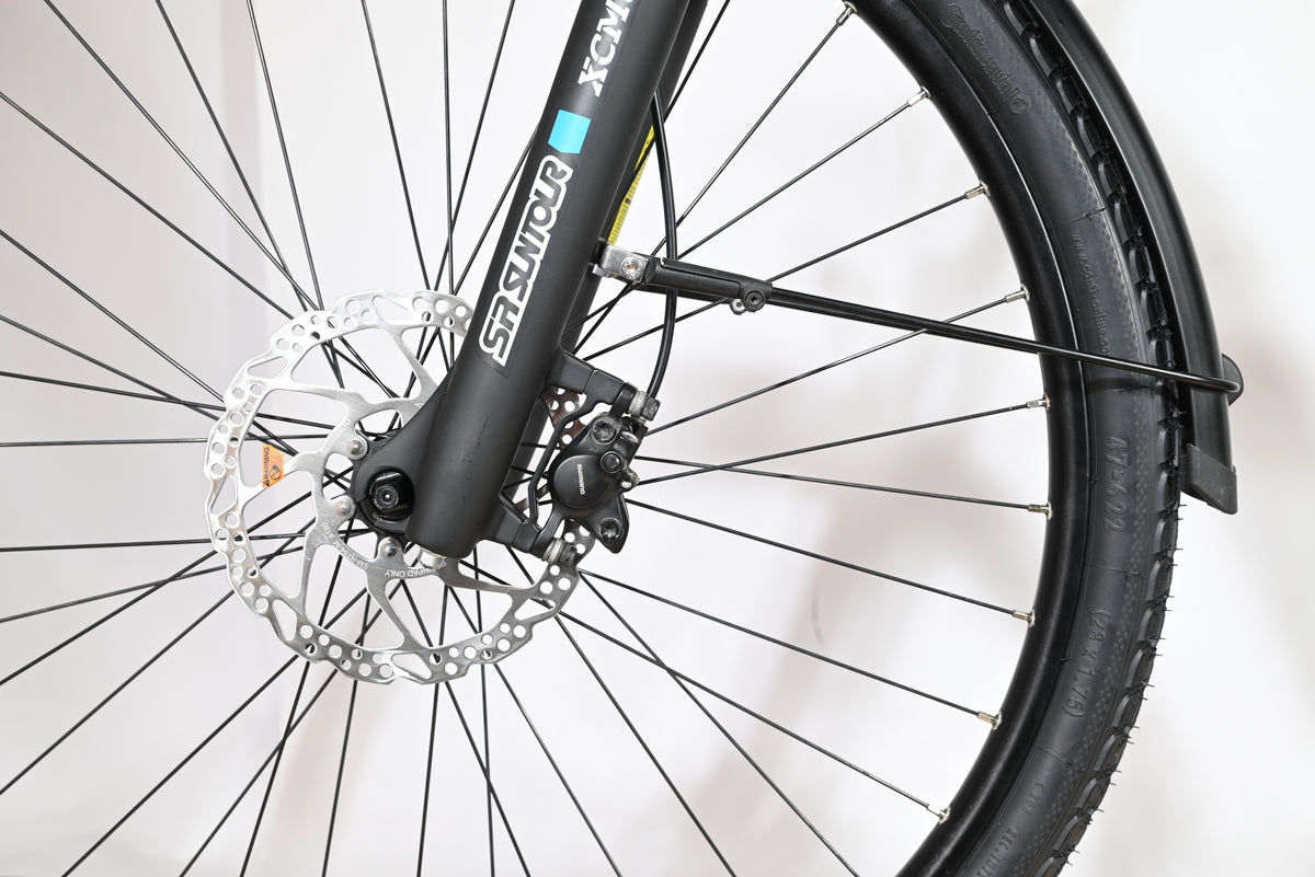 Gros plan sur la roue avant, le frein à disque et la fourche SR Suntour du vélo électrique Loop Sports Velodeville AEB890