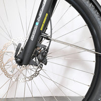 Gros plan sur la roue avant et le frein à disque hydraulique du vélo Loop Sports Victoria Trekking 11.5