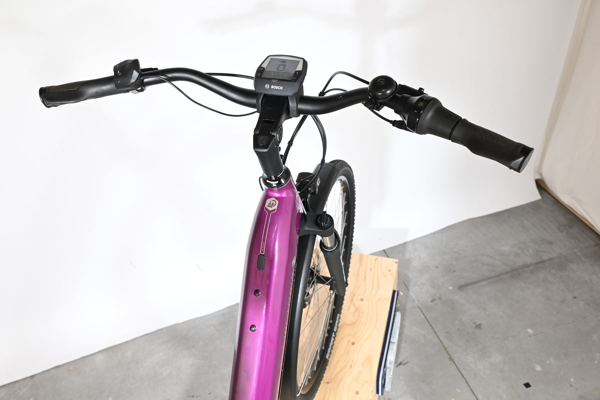 Vue rapprochée du guidon et du cadre violet du vélo électrique Victoria Trekking 11.5 de Loop Sports