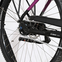 Gros plan sur la roue arrière et le cadre violet du vélo électrique Loop Sports Victoria Trekking 11.5 avec moteur Bosch