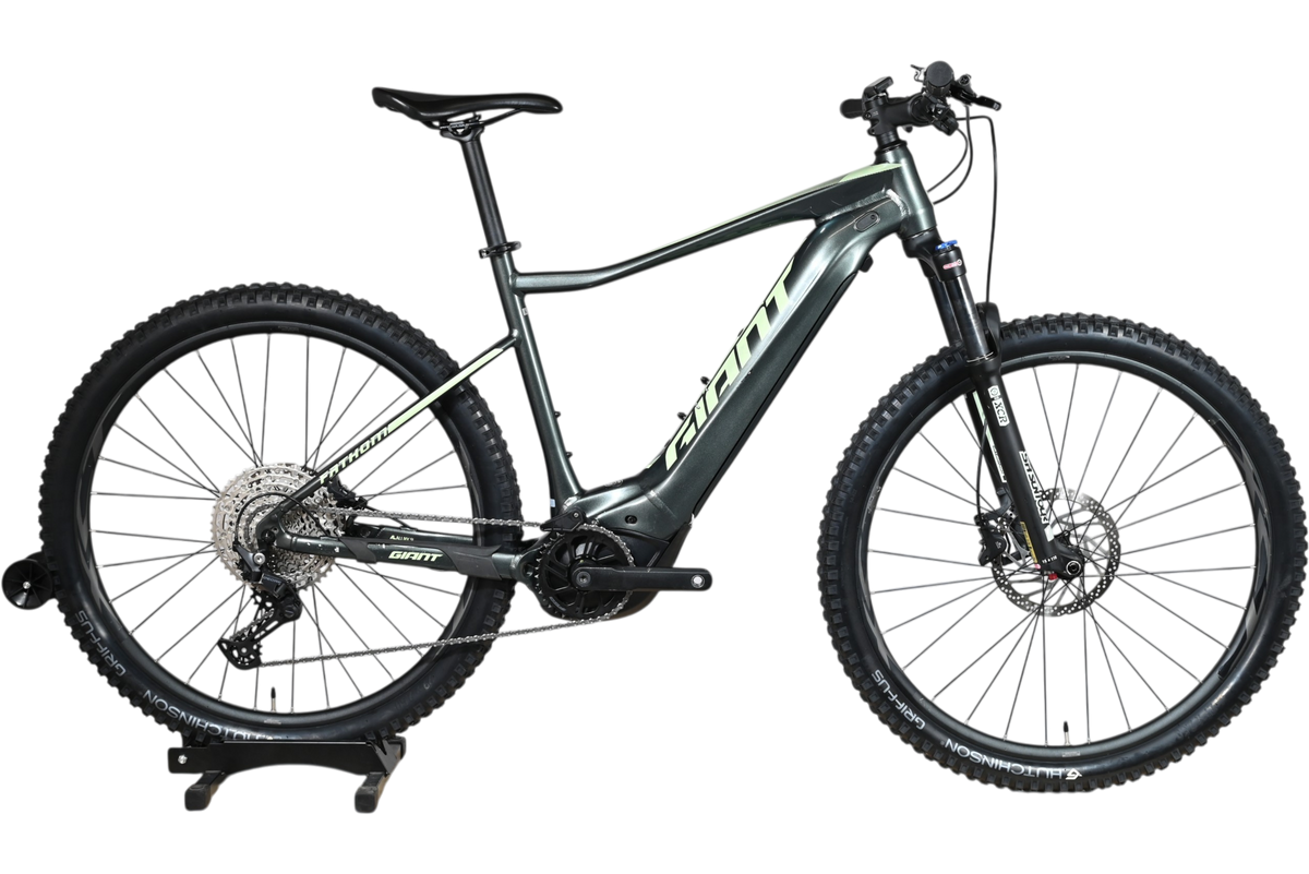 VTT électrique Giant Fathom E+1 2022 gris foncé de Loop Sports sur un support en bois