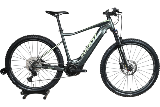 VTT électrique Giant Fathom E+1 2022 gris foncé de Loop Sports sur un support en bois