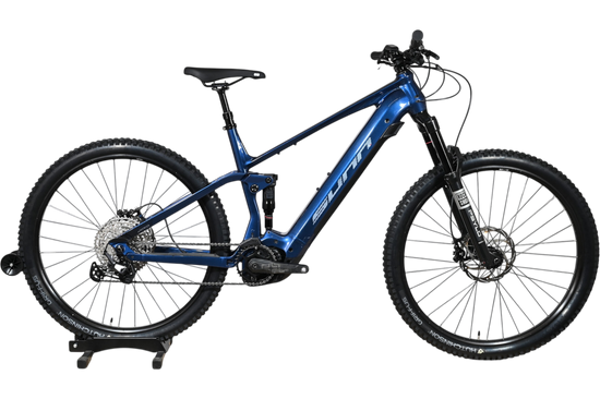 VTT électrique Sunn Charger S1 bleu de Loop Sports, cadre tout-suspendu avec pneus Hutchinson sur socle en bois