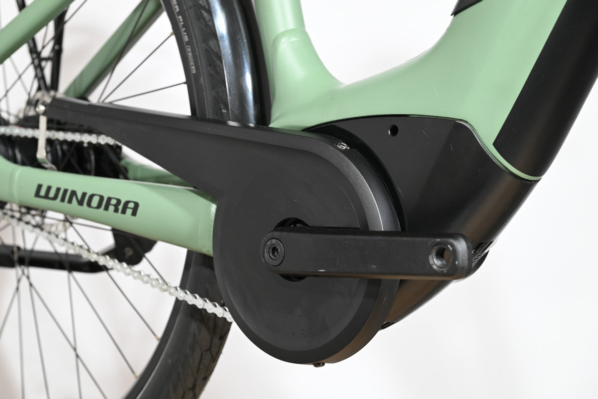 Gros plan sur le moteur central et le pédalier noir du vélo électrique Loop Sports Winora Sinus Tria N8 vert pastel