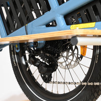 Gros plan sur le dérailleur arrière et la roue du vélo cargo électrique bleu Loop Sports Yuba Spicy Curry 2025