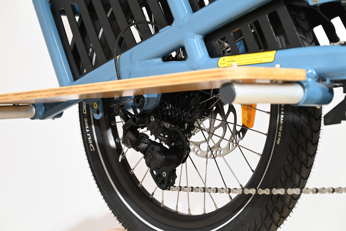 Gros plan sur le dérailleur arrière et la roue du vélo cargo électrique bleu Loop Sports Yuba Spicy Curry 2025