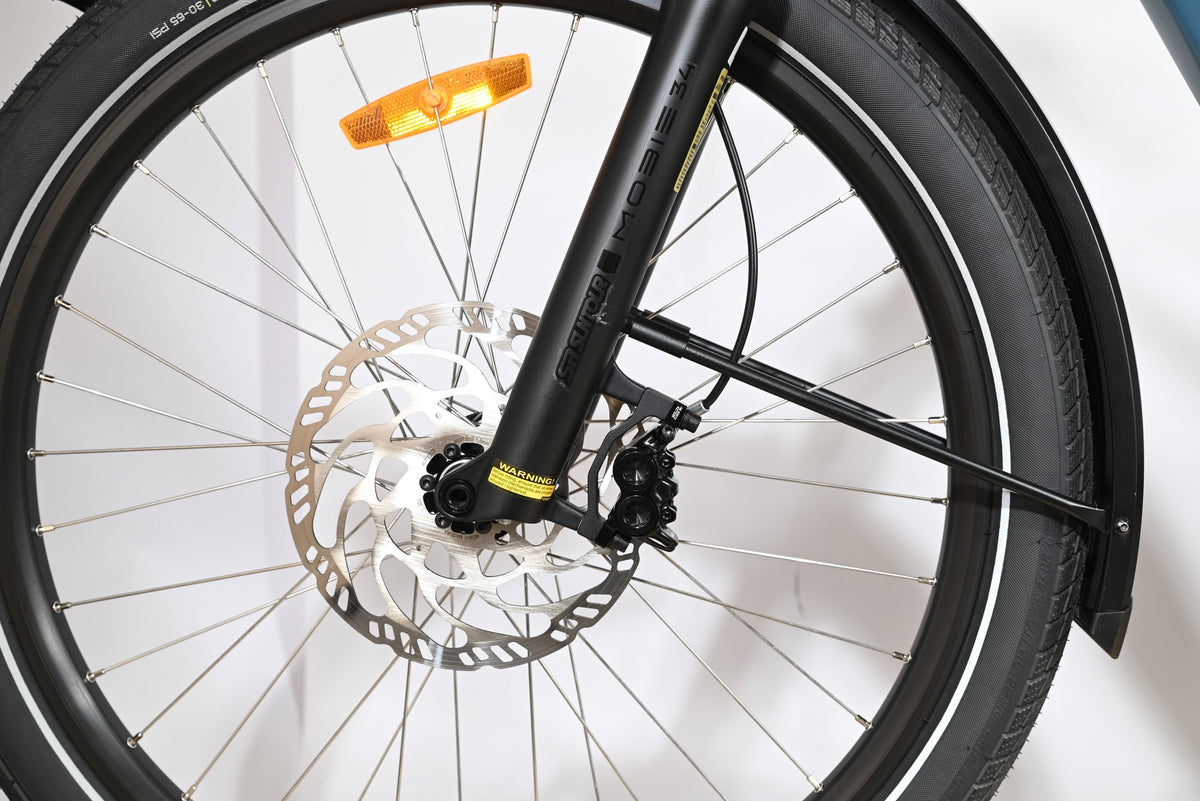 Gros plan sur la roue avant et la fourche suspendue SR Suntour Mobie 34 du vélo cargo Loop Sports Yuba Spicy Curry